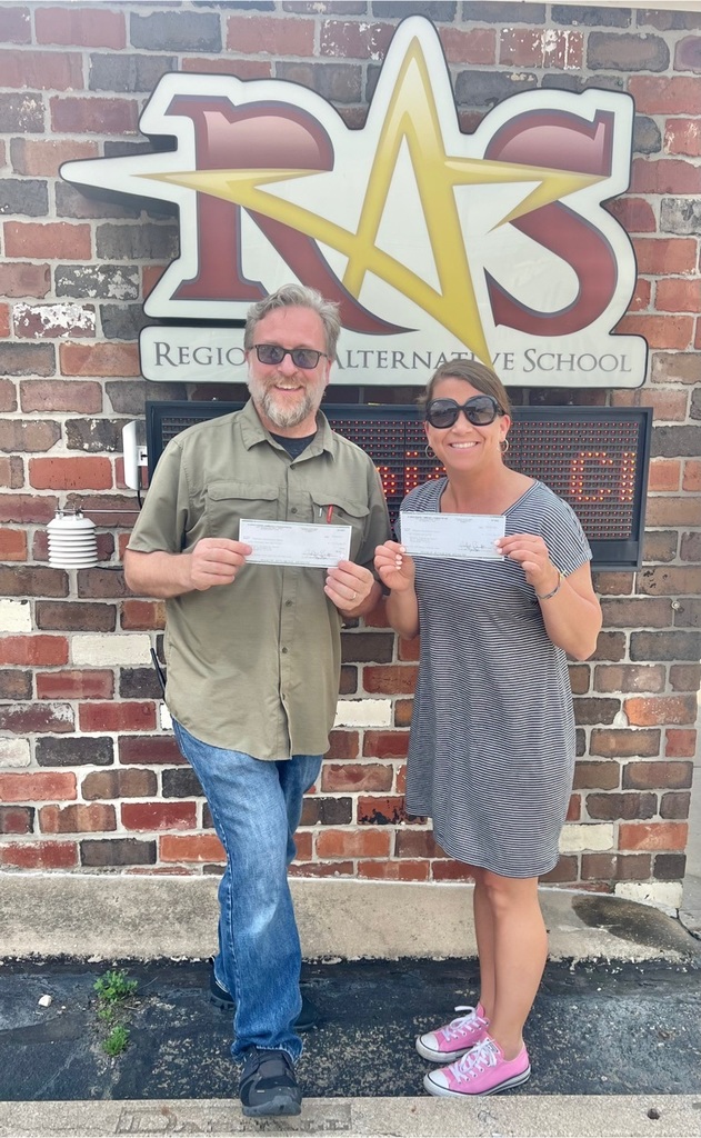 Mr Thornton and Mrs quick with IPCF grant checks in front of RAS sign